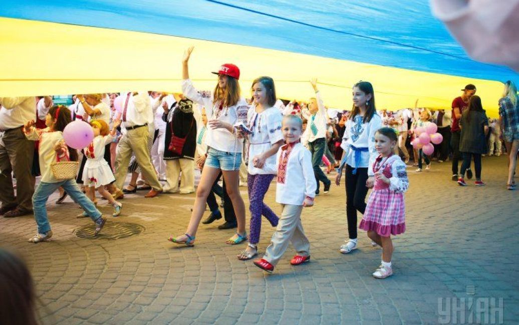 Дети в вышиванках бегают под огромным флагом Украины, который развернули в Ивано-Франковске во время парада вышиванок. 23 августа в Украине отмечают День Государственного флага. / © УНИАН