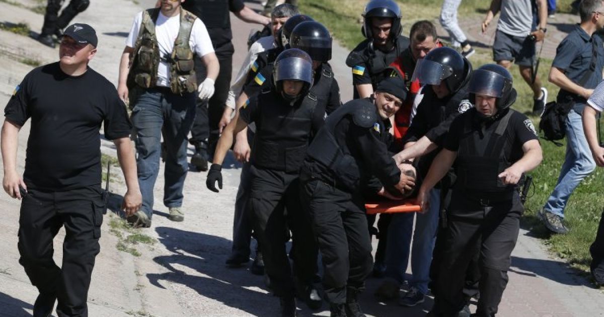 Милиционеры несут своего раненого коллегу до кареты "скорой помощи"