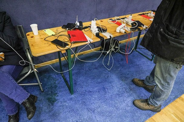 Люди заряжают свои телефоны в импровизированном пункте помощи Немецкого Красного Креста в местном баскетбольном зале / © Getty Images