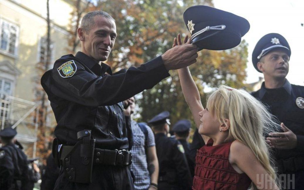 Новый львовский полицейский надевает фуражку на свою дочь. 23 августа во Львове более 400 сотрудников новой патрульной полиции приняли присягу. / © УНИАН
