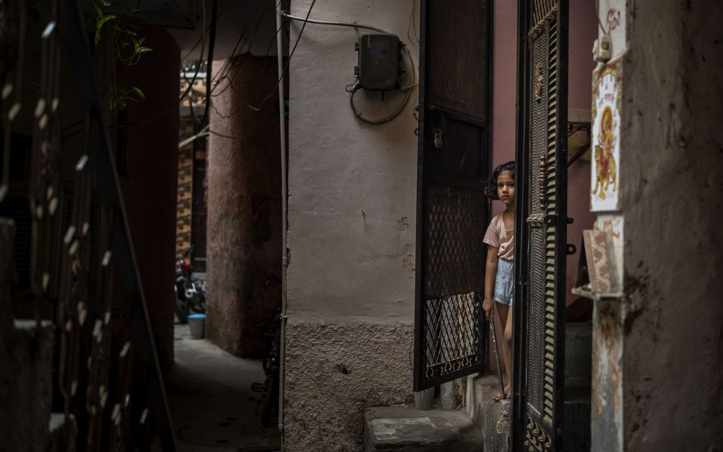 Маленька дівчинка стоїть біля входу в свій будинок неподалік дому вбитої 9-річної дівчинки / © Associated Press