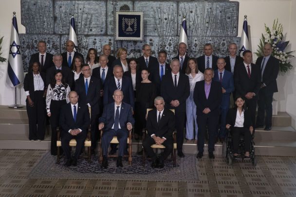 Нафталі Беннетт (сидить ліворуч), десятий президент Ізраїлю Реувен Рівлін (сидить в центрі), наступник прем'єра та міністр закордонних справ Яір Лапід (сидить праворуч) позують для спільної фотографії з міністрами нового уряду.