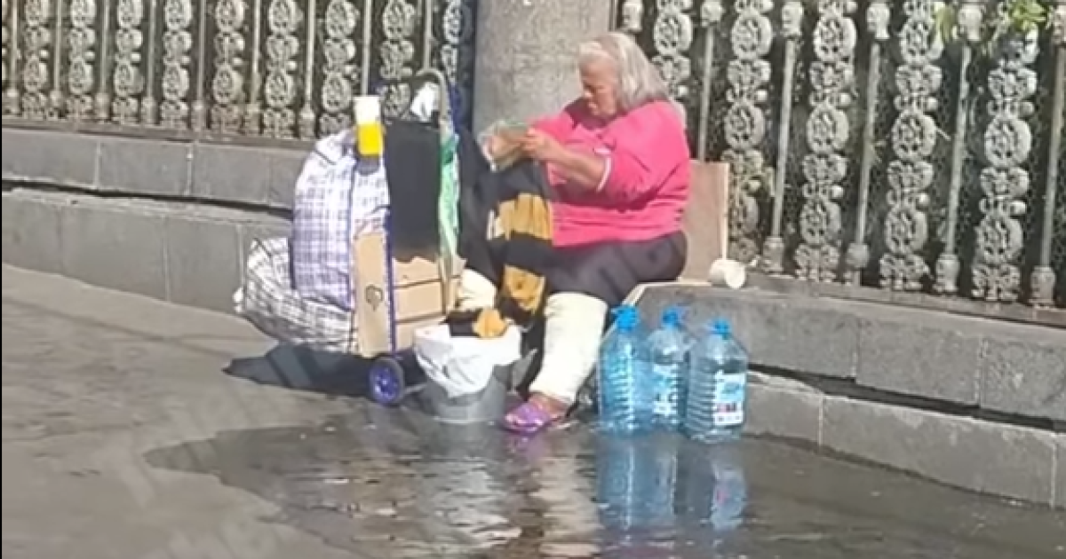В Киеве на вокзале бездомная стирает вещи прямо на тротуаре и выливает воду под ноги прохожим: видео