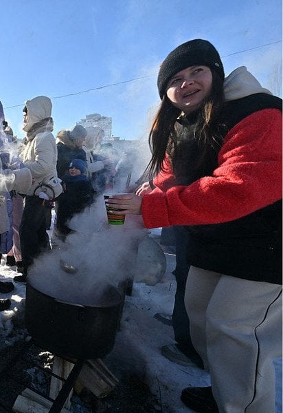 Волонтерка роздає гарячі напої учасникам вечірки з діджеєм просто неба в Києві