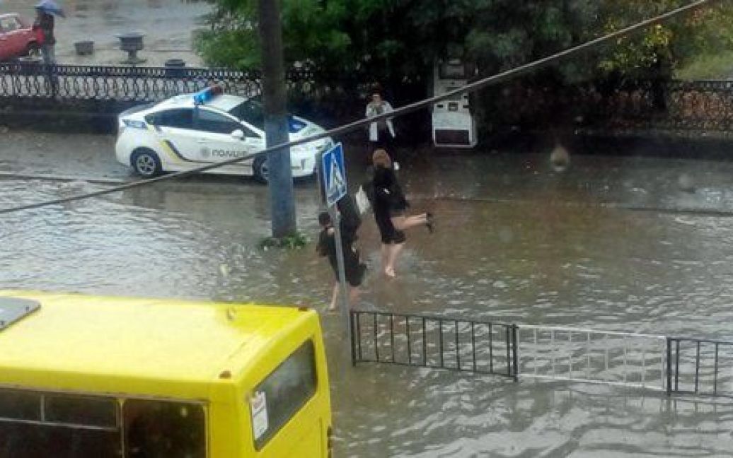 Полицейские переносят пассажиров маршруток через затопленную дорогу / © Вконтакте/govarta1