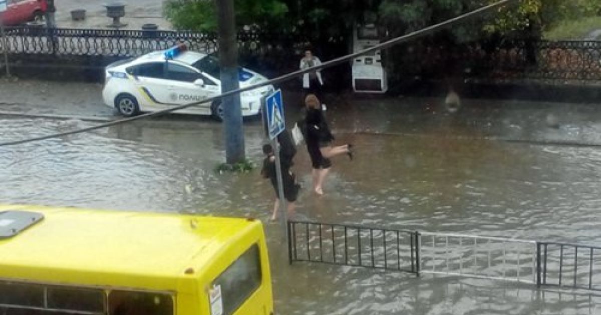 Полицейские переносят пассажиров маршруток через затопленную дорогу / © Вконтакте/govarta1