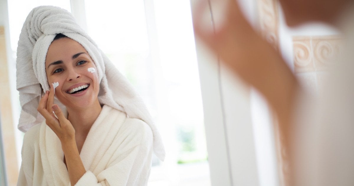 Жінка наносить на обличчя крем