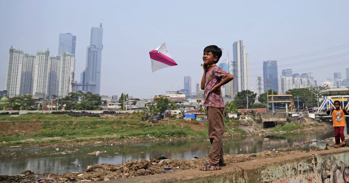 Мальчик играет с воздушным змеем на фоне городского "пейзажа" в Джакарте, Индонезия, 11 августа 2023 года/Associated Press