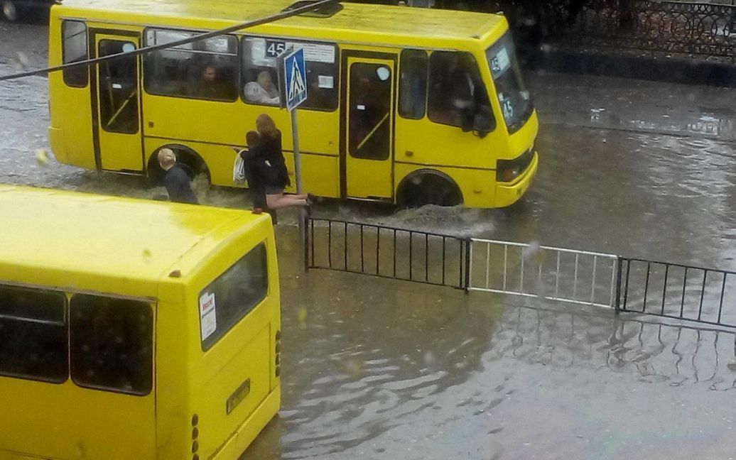 Полицейские переносят пассажиров маршруток через затопленную дорогу / © Вконтакте/lviv_go
