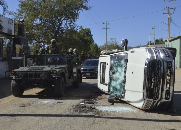 Армійські солдати проїжджають повз зруйнований автомобіль на вулицях Хесус Марія, Мексика, в суботу, 7 січня 2023 року, в невеликому містечку, де на початку тижня був затриманий Овідіо Гусман / © Associated Press