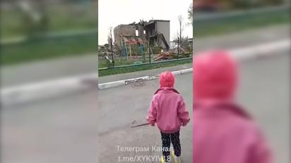 Ребенок плачет перед руинами своего разрушенного детского сада