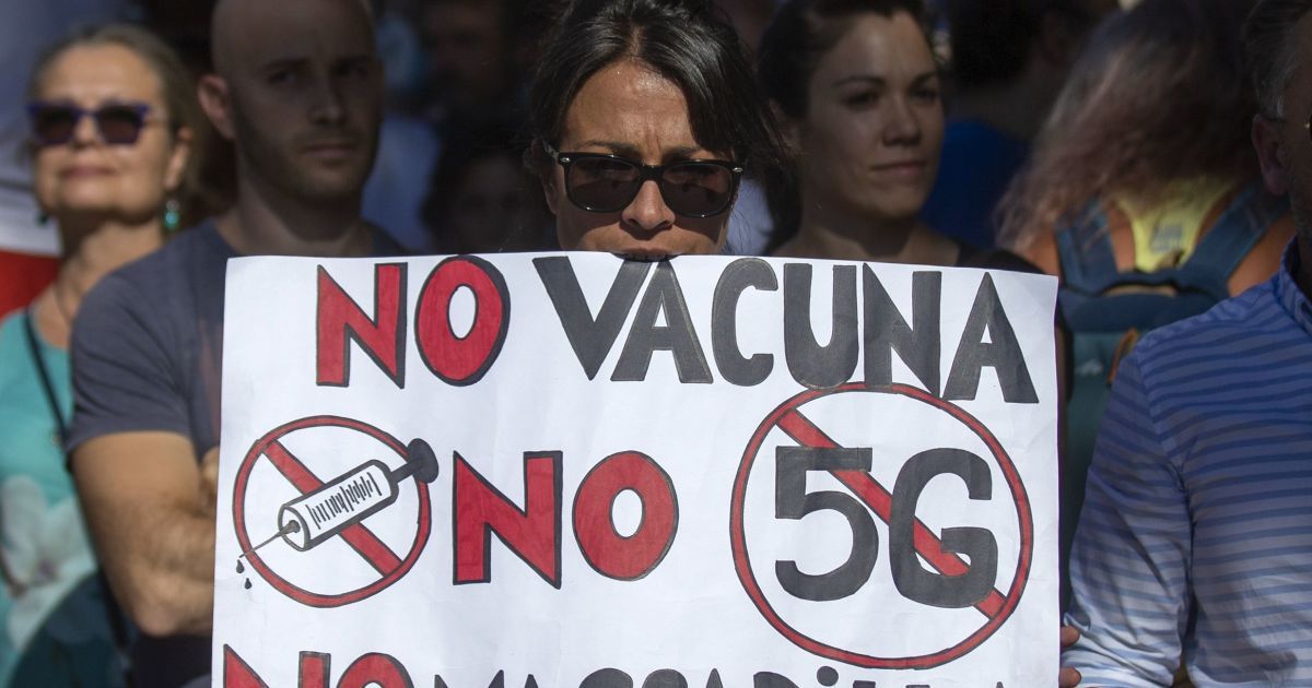 Протестувальниця в Мадриді тримає плакат з написом "Ні вакцинації. Ні 5G. Ні маскам".