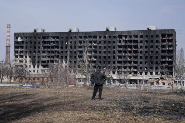 A man looks at a burned apartment building that was damaged by shelling in Mariupol / © Associated Press