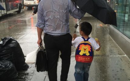 Пользователей Сети умилило фото заботливого отца, который защитил своего сына от ливня