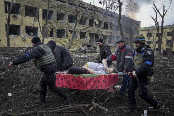 Russian emergency employees and volunteers carry injured pregnant woman from a maternity hospital that was damaged by shelling / © Associated Press
