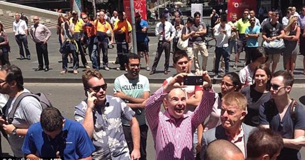 Веселий чоловік фотографує кафе у Сіднеї, під час того, як там утримували у полоні відвідувачів / © ABC News