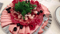 На столах - несколько видов мясной нарезки с салом