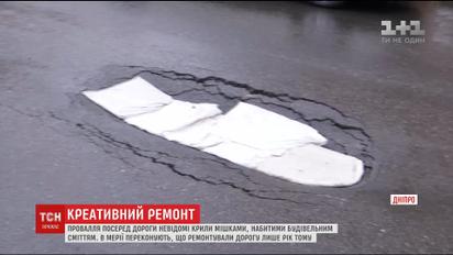 Креативний ремонт: у Дніпрі провалля посеред дороги вкрили мішками зі сміттям