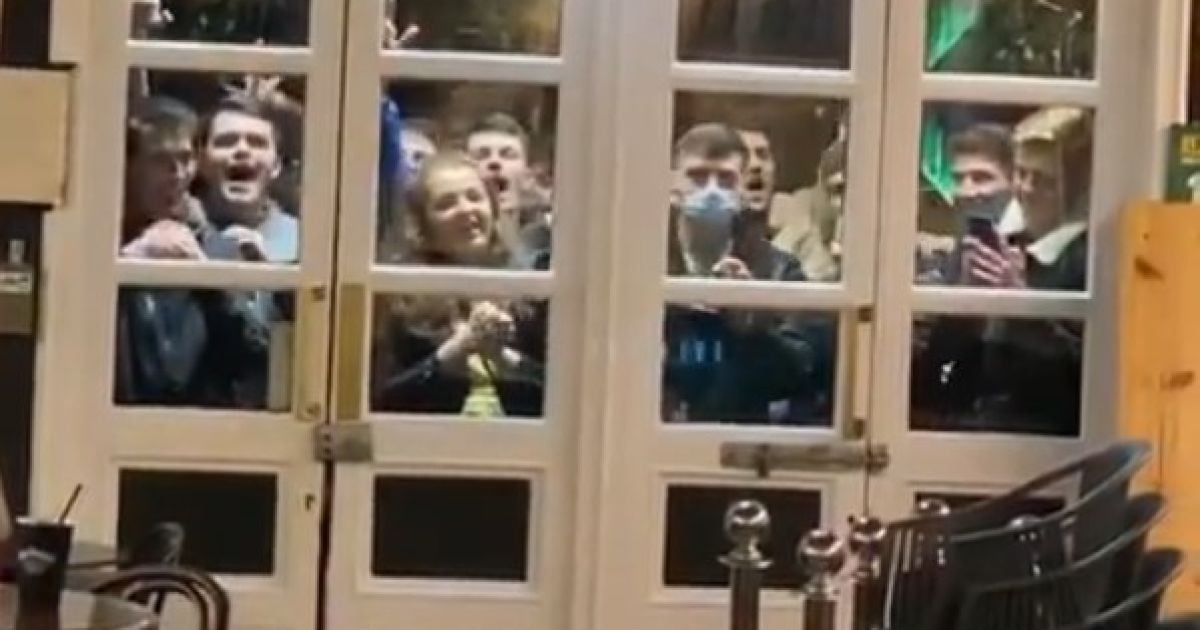 Болельщики смотрят за матчем из окон бара