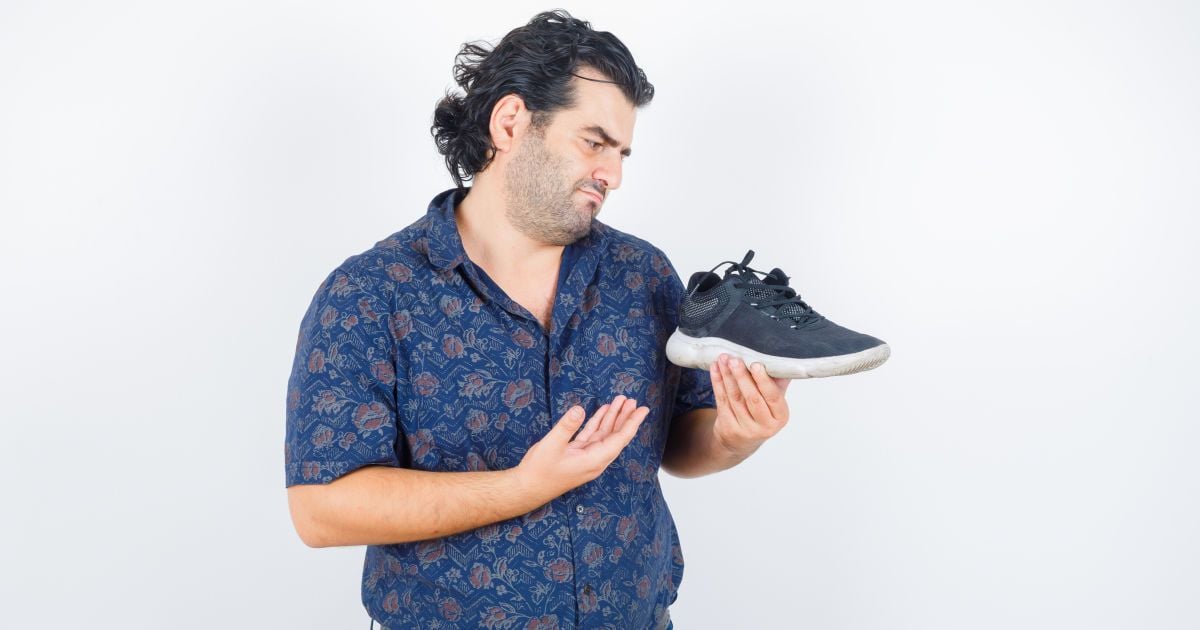 Чоловік із кросівком у руках