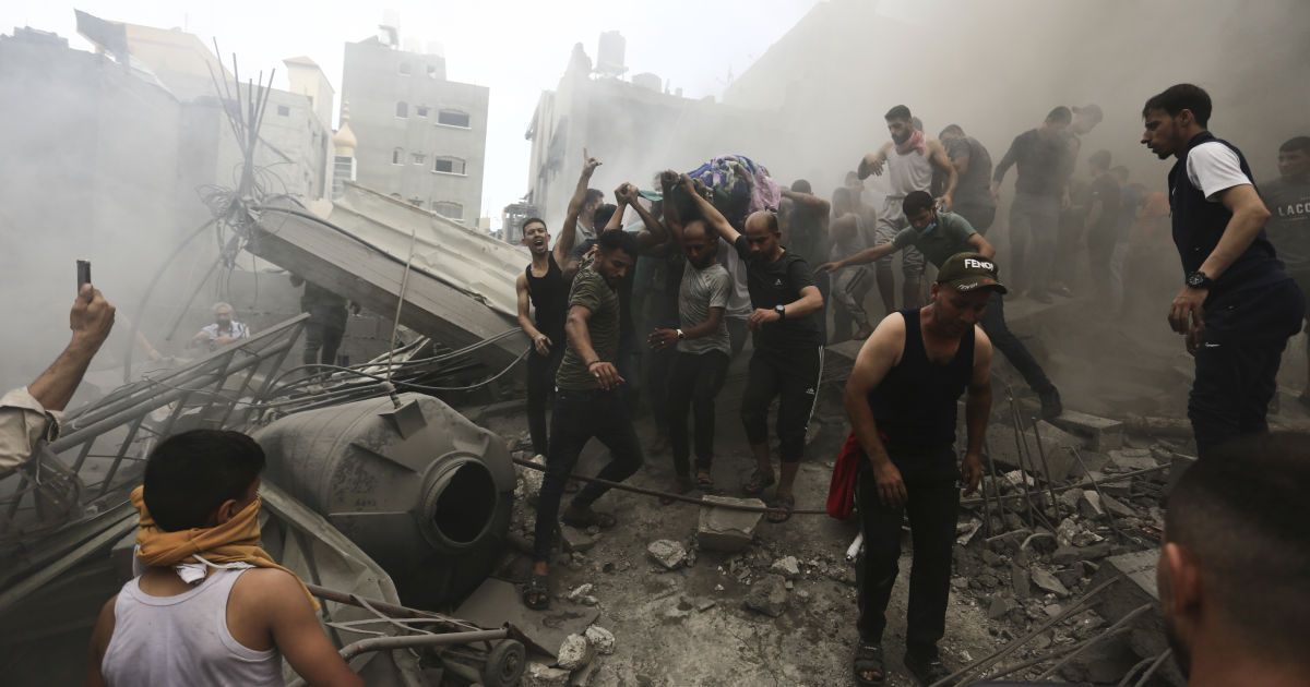 Палестинцы достают тело мертвого из-под обломков здания после израильского авиаудара по Сектору Газа