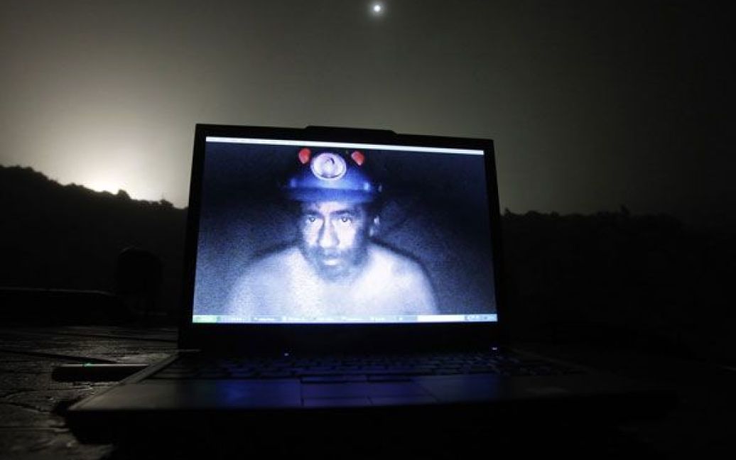 Фото Івана Альварадо. Чилі, Копіапо. На екрані &ndash; чилійський шахтар Джонні Барріос. 33 чилійські шахтарі опинились у пастці на глибині більше 700 метрів, де вони провели 69 днів. / © Reuters