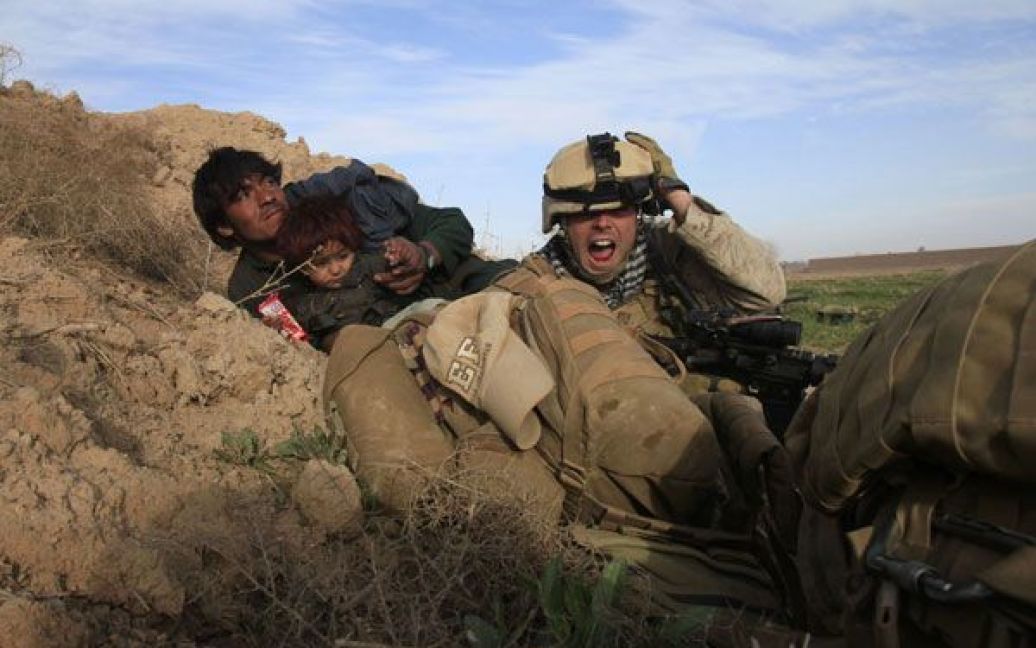 Фото Горана Томашевича. Афганістан, провінція Гільменд. Морський піхотинець США з 1-го батальйону, який брав участь у кампанії "Браво", під час наступу на активістів руху Талібан у їхньому оплоті, Марджі, провінція Гільменд, прикриває від вогню афганця і його сина. / © Reuters