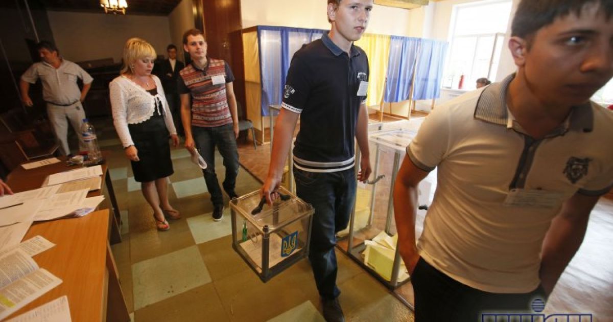 Члени виборчої комісії несуть урну з бюлетнями для голосування на дому на одній із виборчих дільниць Василькова