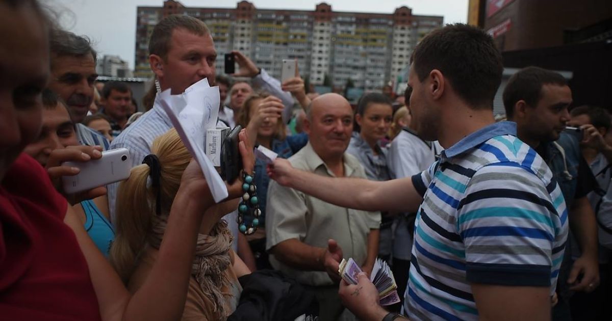 Мужчина из команды Ляшко раздает жителям Троещины в Киеве деньги, которые изъяли в незаконном казино / © facebook.com/O.Liashko