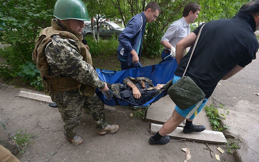Чоловіки несуть тіло вбитого терориста в Луганську 2 червня / © gazeta.ru
