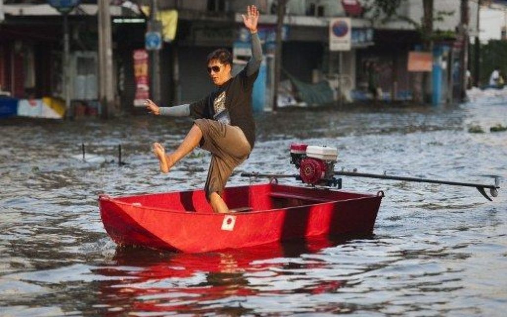 Таїланд, Бангкок. Чоловік балансує у човні під час перетину затопленої вулиці у Бангкоку. Столиця Таїланду, побудована на болоті, повільно йде під воду. / © AFP