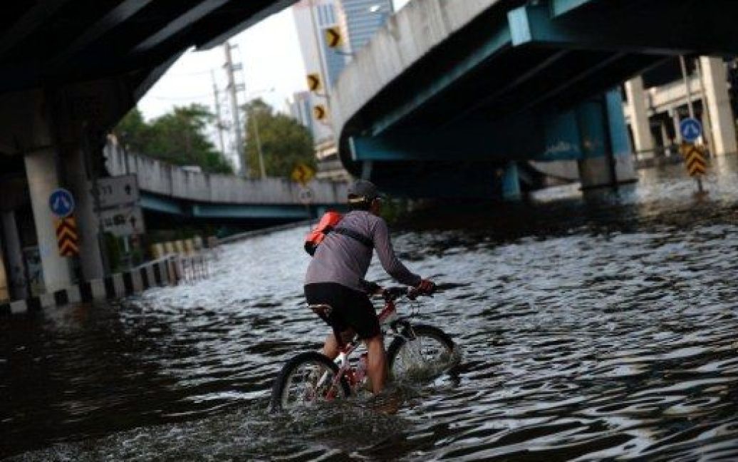 Таїланд, Бангкок. Людина їде на велосипеді проти течії у затопленому в результаті повені районі Mo Чіт у Бангкоку. Більше 529 осіб було вбито під час найгіршої повені в історії Таїланду. / © AFP
