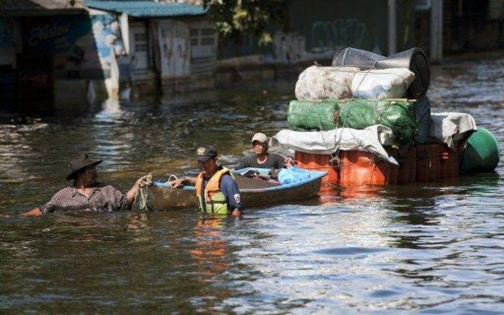 Таїланд, Бангкок. Люди перевозять свої речі на човнах та плотах через затоплені вулиці поблизу аеропорту "Дон Муанг" у Бангкоку. Жителі затоплених районів Бангкоку виступають за демонтаж основних доріг, які блокують відтік води з їхніх районів. / © AFP