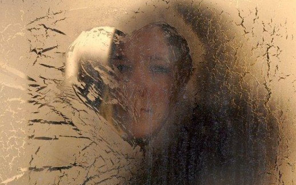 Білорусь, Мінськ. Жінка дивиться зі вкритого інеєм вікна автобуса в Мінську, де температура впала сьогодні до - 27 градусів за Цельсієм. / © AFP