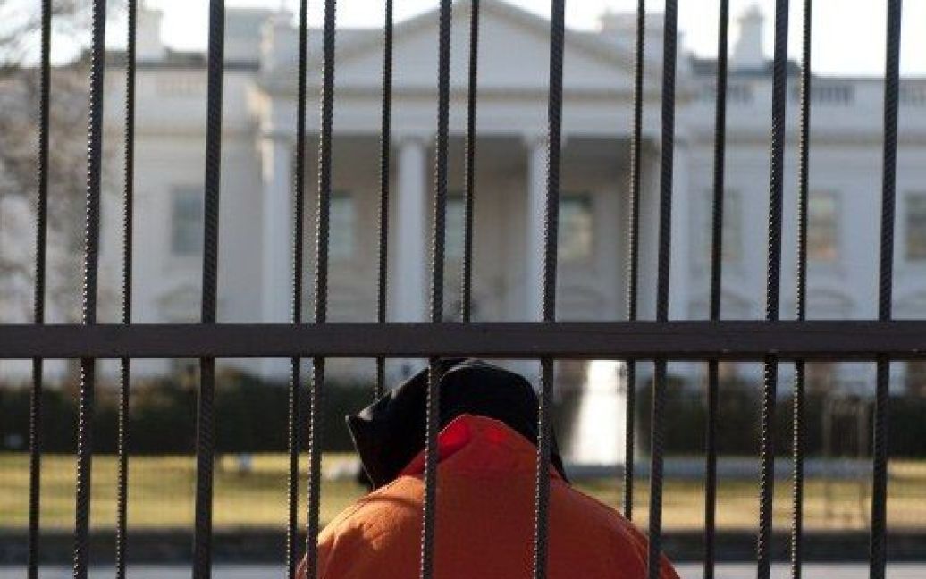 США, Вашингтон. Людина у помаранчевому костюмі в&#039;язня і капюшоні на голові сидить у клітці під час демонстрації перед Білим домом у Вашингтоні. Учасники акції закликали уряд закрити в&#039;язницю Гуантанамо. / © AFP