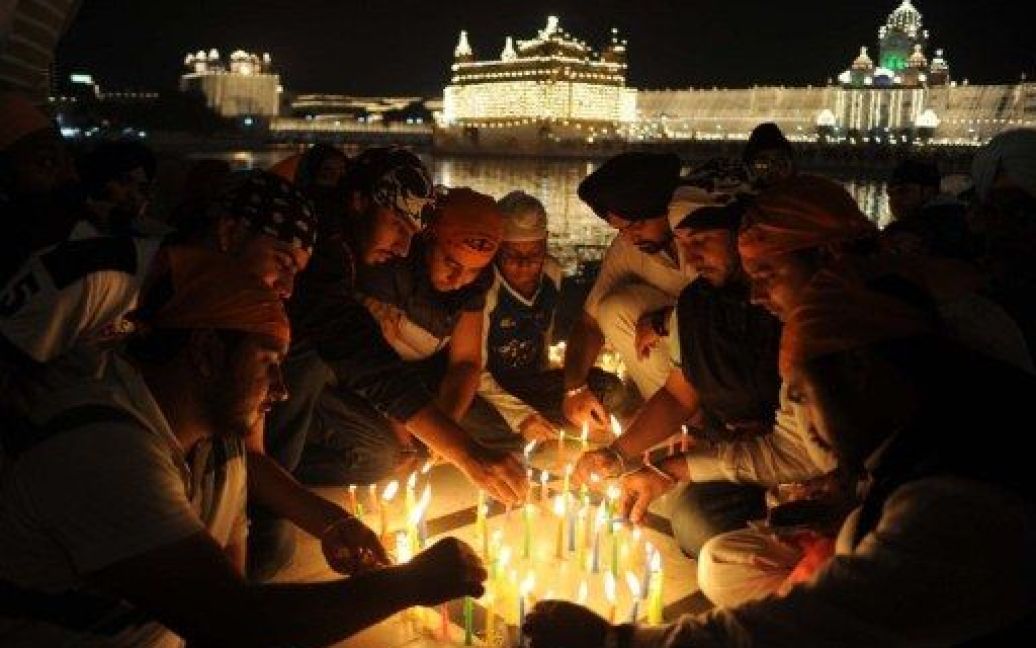 Індія, Амрітсар. Індійські сикхи запалюють свічки під час церемонії вшанування перед Золотим храмом у Амрітсарі. / © AFP
