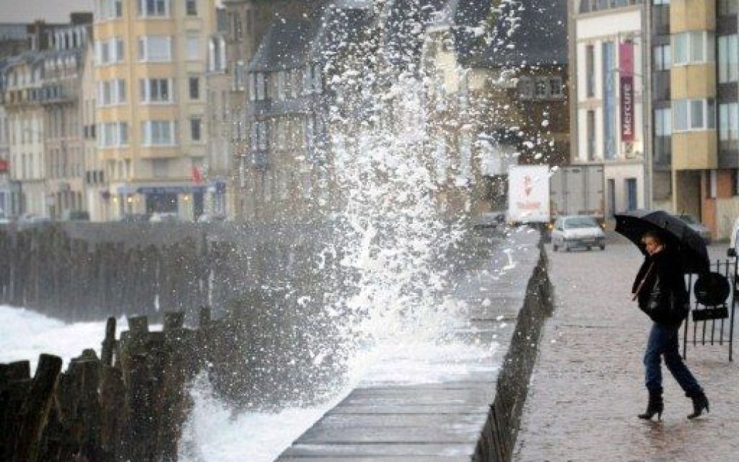 Франція, Сен-Мало. Жінка з парасолькою дивиться на хвилі на набережній міста Сен-Мало. Сильні пориви вітру на західному та північному узбережжі Франції принесли з собою зимовий холод. / © AFP