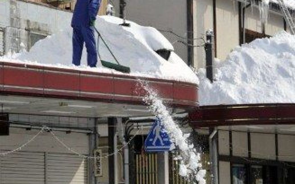 Японія, Токаматі. Мешканці прибирають сніг з дахів у торговому районі Токаматі у префектурі Ніїгата. Сильний снігопад завалив більшість районів країни. / © AFP