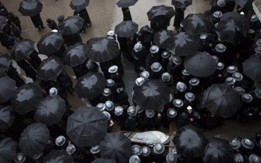 Єрусалим. Під сильним дощем ультра-ортодоксальні євреї тримають парасольки і закривають капелюхи пластиковими пакетами під час похорону рабина Нафталі Розенфельда, які помер у віці 99 років. / © AFP