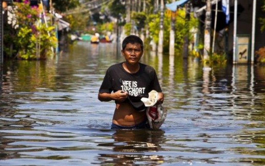Таїланд, Бангкок. Чоловік йде затопленою вулицею на півдні Бангкоку. Влада країни заявила, що частина міста залишиться затопленою до наступного року, незважаючи на те, що вода спадає. / © AFP