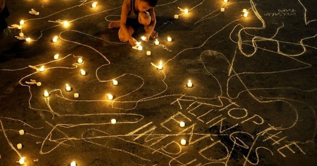 Філіппіни, Маніла. Хлопчик запалює свічку під час служби з нагоди другої річниці різанини у Магінданао. Родичі 57 загиблих у найгіршій політичні бійні в країні закликали владу прискорити суд над підозрюваними у злочині. / © AFP