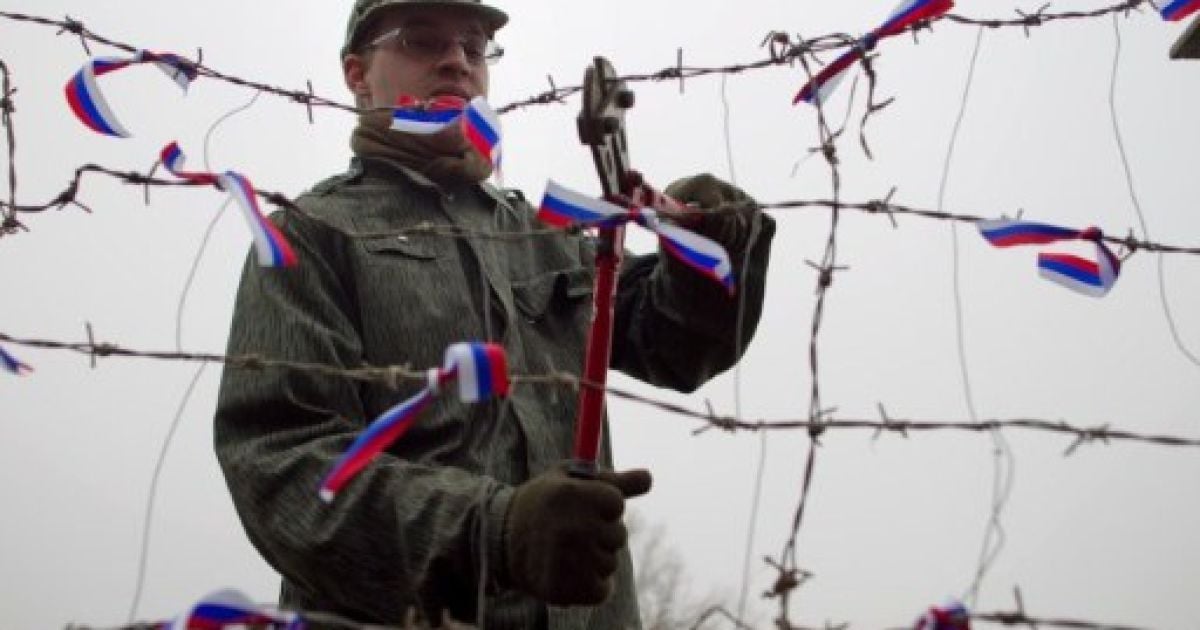 Словаччина, Братислава. Людина перерізає колючий дріт, символ залізної завіси, поруч із словацько-австрійським кордоном в Братиславі. Акцію провели на честь 22-ї річниці "оксамитової революції" 1989 року, мирного перевороту, який повалив комунізм у Чехословаччині. / © AFP