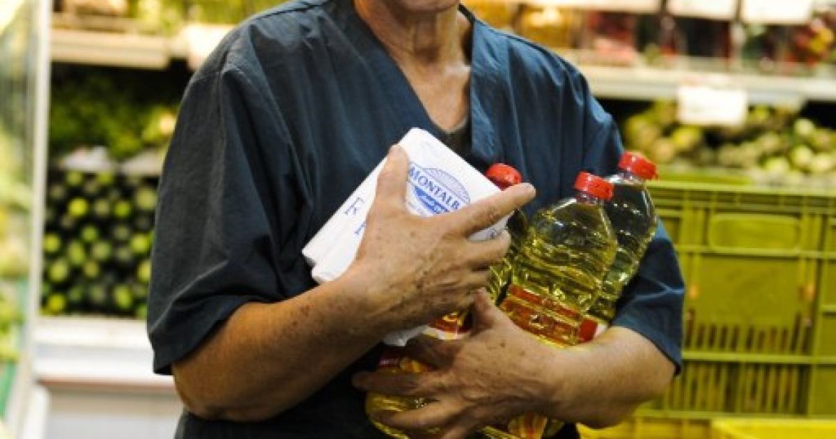 Венесуела, Каракас. Жінка несе пакунки з цукром і пляшки рослинного масла. В країні очікують високу інфляцію та швидке зростання цін після прийняття закону про контроль цін на всі товари і послуги. / © AFP