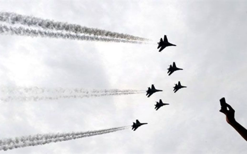 Індонезія, Джакарта. Індонезієць фотографує російський реактивний винищувач "Сухий", який маневрує під час святкування 65-річчя індонезійської армії у Джакарті. / © AFP