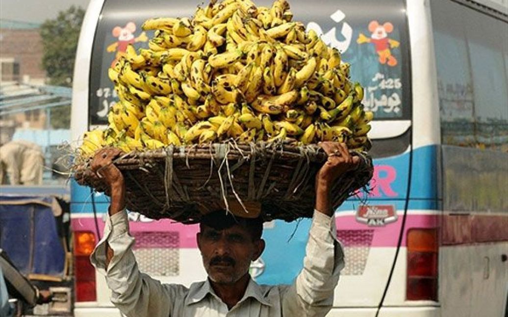 Пакистан, Лахор. Пакистанець несе велику корзину з бананами на фруктовий ринок у Лахорі. Центральний банк Пакистану підняв процентну ставку до 13,5 відсотків, попереджаючи, що інфляція, як і раніше, істотно впливає на економіку. / © AFP