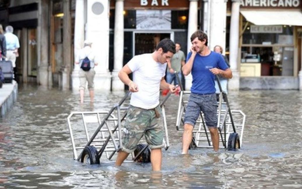 Італія, Венеція. Робочі штовхають візки на затопленій площі Сан-Марко у Венеції. / © AFP