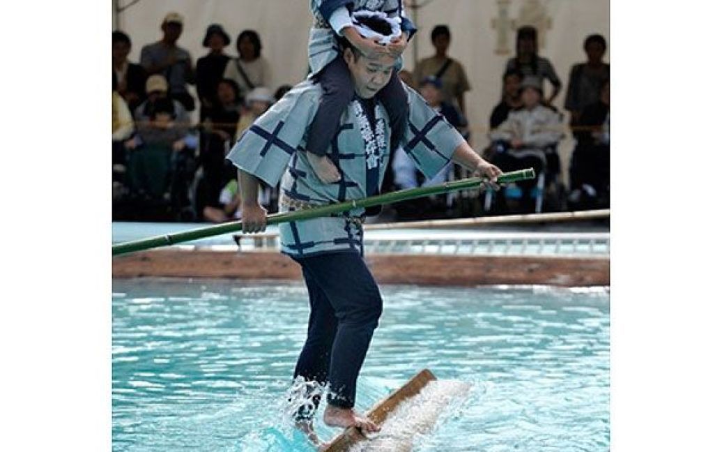 Японія, Токіо. Перевізник, член товариства "Кіба", виконує трюк на плаваючому брусі під час фестивалю в Токіо. Подібний "трюк" зазвичай виконували лісоруби  під час своєї щоденної роботи за часів династії Едо (1603-1868 рр.), коли вони сплавлялись, стоячи на колодах. / © AFP