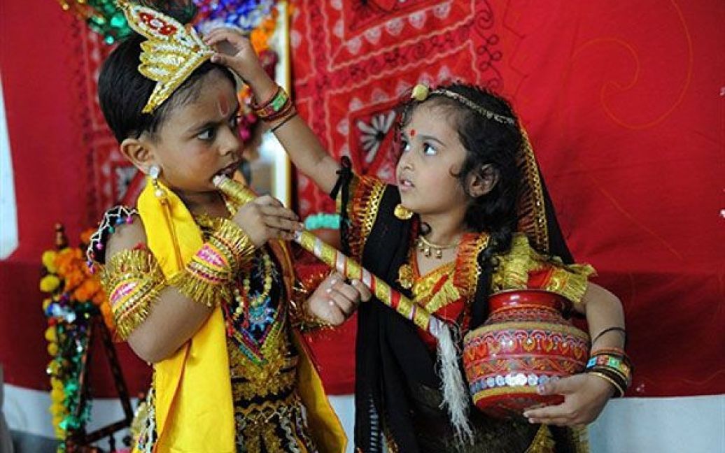 Індія, Ахмедабад. Індійський хлопчик, одягнений у костюм індуїстського бога Крішни, дивиться на дівчинку, одягнену як Рада, доки та поправляє на хлопчикові корону. В Індії відзначили свято Матка Пход (розбивання глечику), яке відбувається напередодні дня народження Крішни &mdash; Джанмаштамі. / © AFP