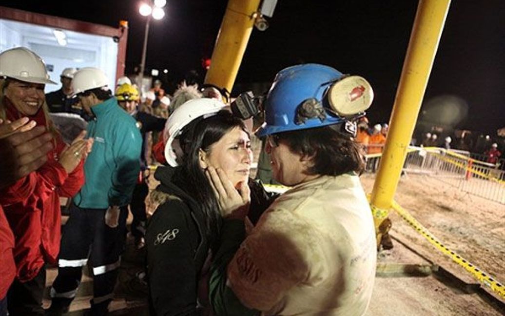 Чилі, Копіапо. Чилійський шахтар Осман Арайя обнімає свою дружину Анжеліку після того, як його підняли на поверхню у капсулі "Фенікс". У Чилі було завершено операцію з порятунку 33 шахтарів, які провели у підземній пастці в заваленій шахті Сан-Хосе 70 днів. / © AFP