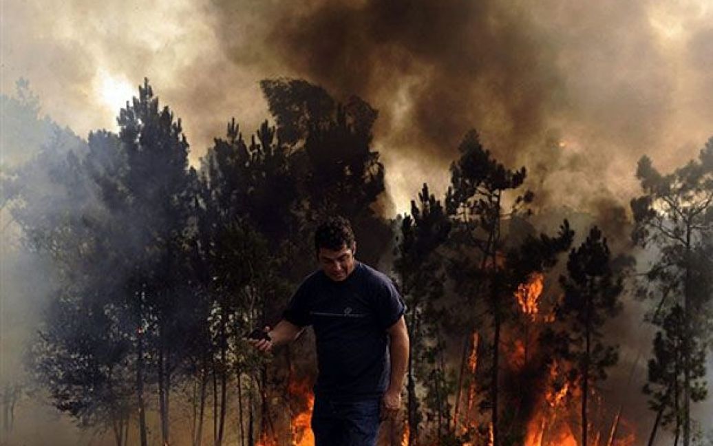 Португалія, Сальвадор. Чоловік з мобільним телефоном йде на тлі лісової пожежі у місті Сальвадор на півночі Португалії. Португальські військові були залучені до гасіння лісових пожеж, які спалахнули на півночі країни. / © AFP